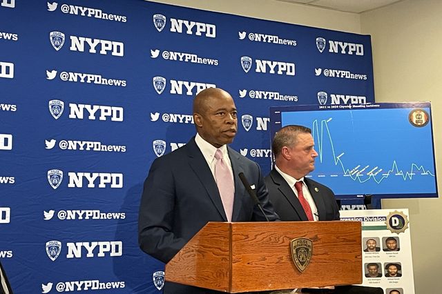 Mayor Eric Adams at a podium with an NYPD drape in the back announcing a drop in shootings.